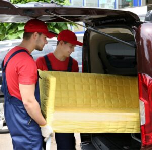 Günstig umziehen in Bitburg: Umzugshelfer laden ein gelbes Sofa in einen Transporter