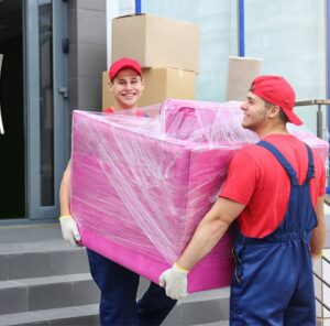 Zwei Umzugshelfer tragen ein in Folie gepacktes Möbelstück – Umzug in Bitburg
