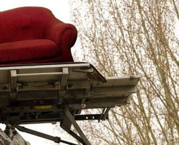 Sofa im Möbellift Rotes Sofa auf der Plattform eines Möbellifts